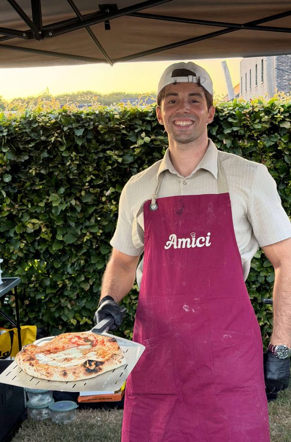David van Amici toont een vers gebakken pizza in de buitenlucht voor pizza- en pastacatering.