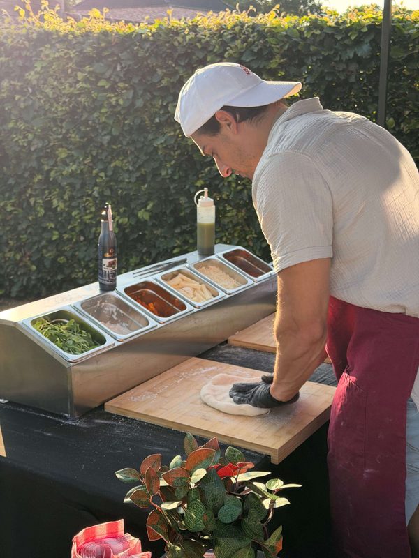 Diego van Amici bereidt een ambachtelijke pizza, ideaal voor pizza- en pastacatering en authentieke Italiaanse foodbeleving.