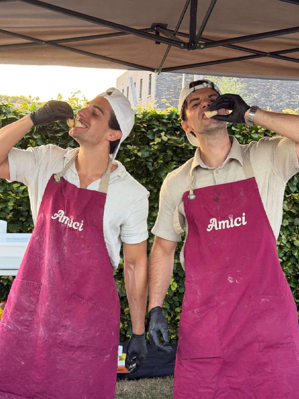De oprichters van Amici catering, Diego en David, poserend in bordeauxrode schorten voor hun Italiaanse pizza- en pastacatering op locatie.