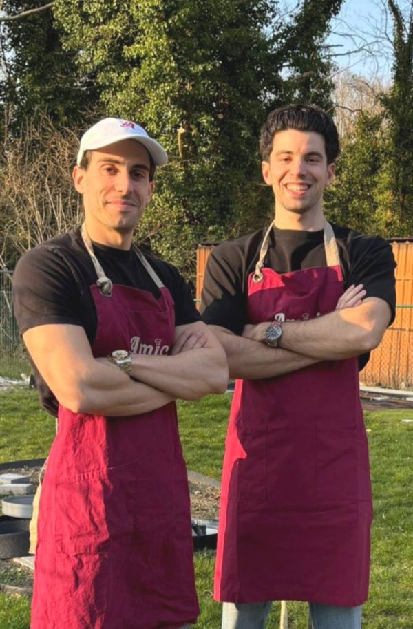 De oprichters van Amici catering, Diego en David, poserend in bordeauxrode schorten voor hun Italiaanse pizza- en pastacatering op locatie.