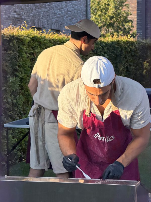 De gepassioneerde chef-koks van Amici aan het werk, waarbij verse ingrediënten buiten worden bereid. Vakmanschap en oog voor detail, vastgelegd in natuurlijk licht.