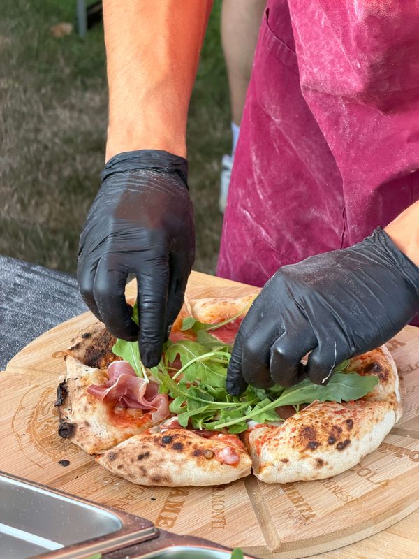 Amici-chef die een pizza Parma bereidt tijdens een cateringevent.